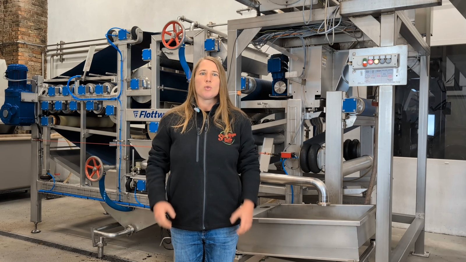 Mitarbeiterin der SonntagsSAFT GmbH vor der Bandpresse in der Produktionshalle